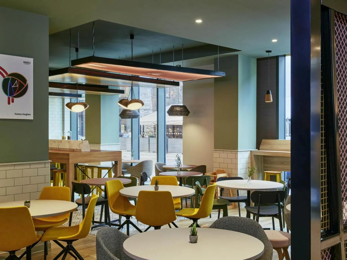 a restaurant with white tables and yellow chairs at Aparthotel Adagio Glasgow Central in Glasgow