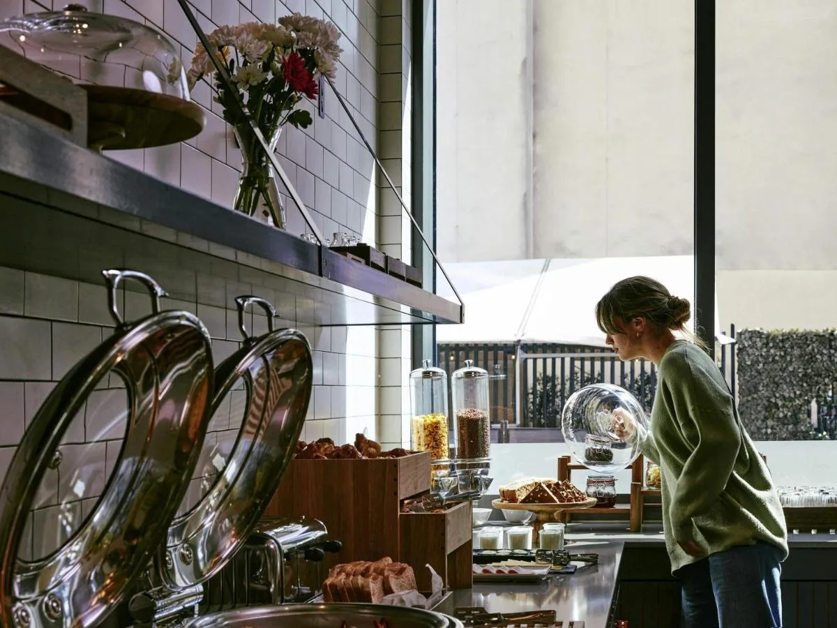 a woman standing in a kitchen preparing food at Aparthotel Adagio Glasgow Central in Glasgow