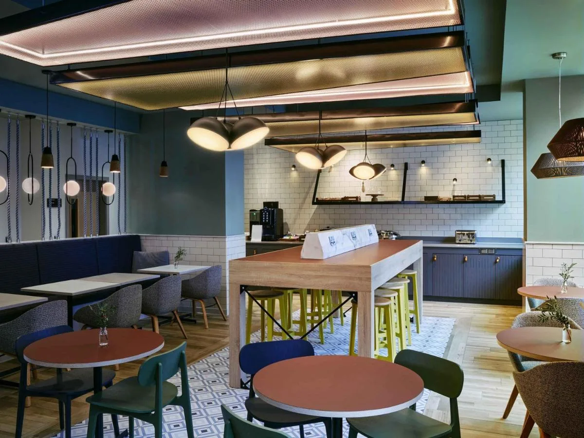 a restaurant with tables and chairs and a kitchen at Aparthotel Adagio Glasgow Central in Glasgow