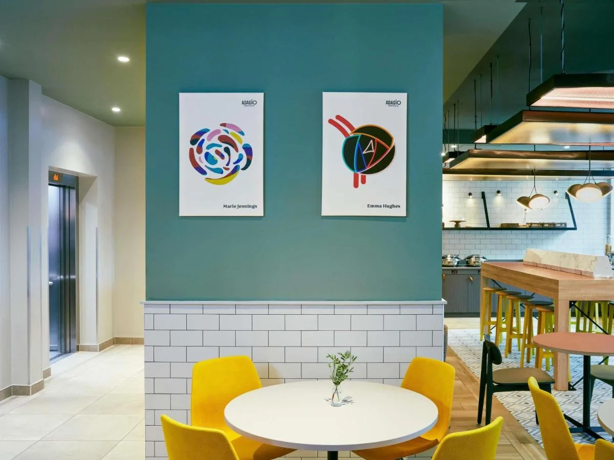a dining room with a white table and yellow chairs at Aparthotel Adagio Glasgow Central in Glasgow